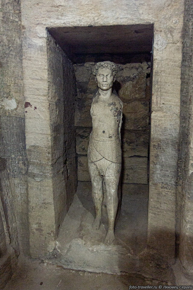  В стенных нишах вырезаны фигуры мужчины и женщины. Тело 
мужчины в строгой иератической позе, 
характерной для древнеегипетской скульптуры, но голова выполнена в эллинистической 
манере.