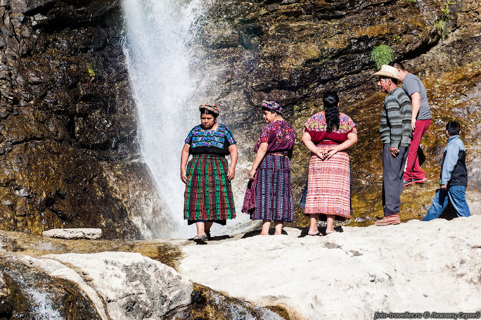 Местные жители фотографируются у небольшого водопада, расположенного 
у дороги, поднимающейся над озером
