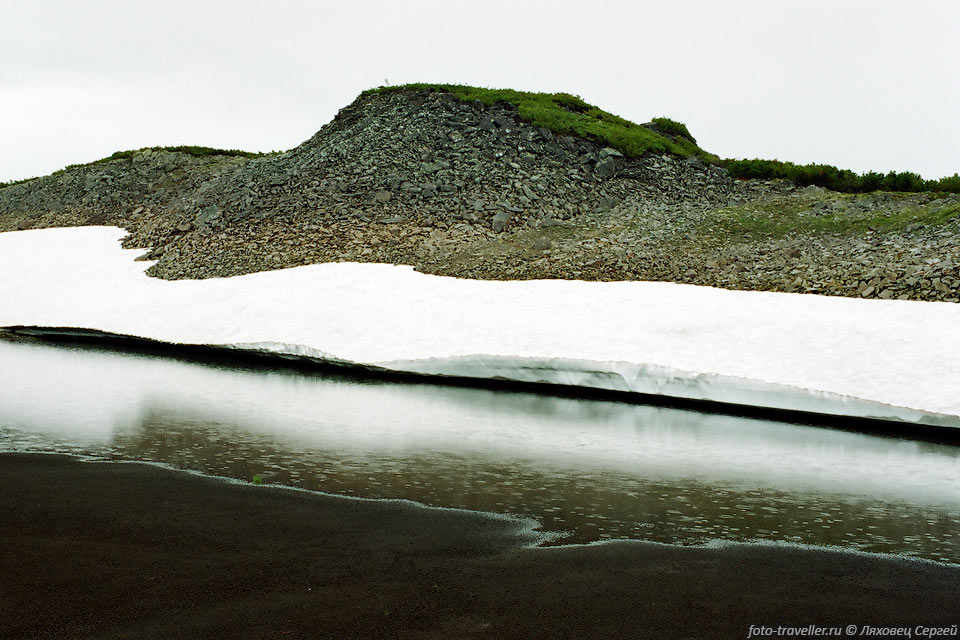 Снежник над озером с дном из мелкого вулканического шлака на склоне 
вулкана Бурлящий