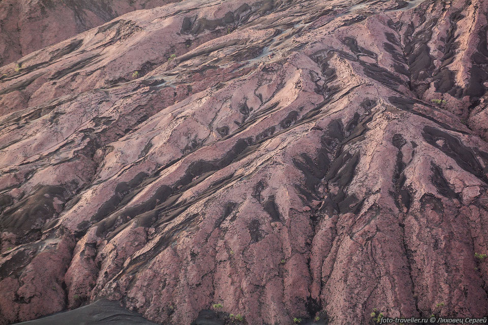 У подножья вулкана Ясур находятся какие-то эрозионные образования 
покрытые красноватой твердой коркой.
Это древний лавовый поток, но почему он такой не ясно.